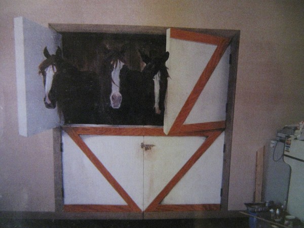 three horses peering from their barn door