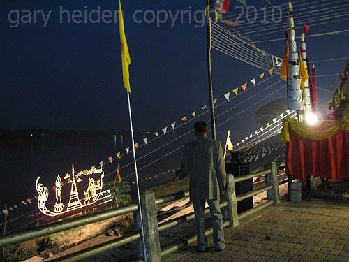 Man Gazing at illuminated float on mekong river