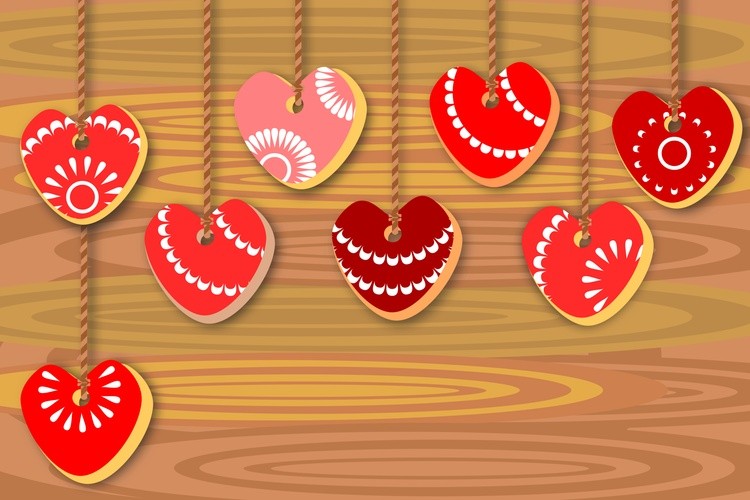 Heart shaped cookies with red icing hanging on a wooden background