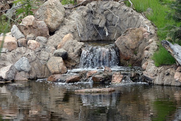 Rock waterfall flowing into a small pond.