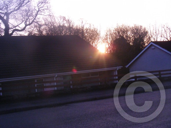 Morning sun rising behind a house