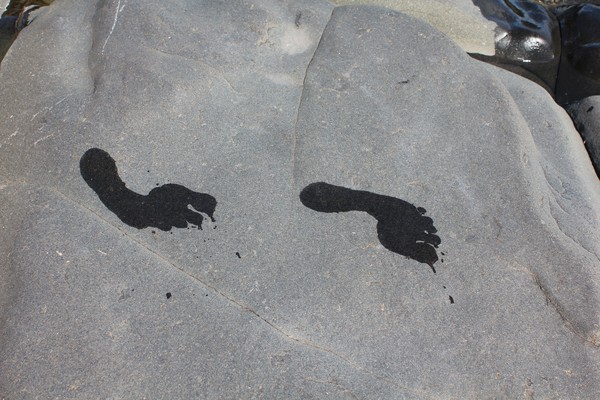 Foot prints on black rock