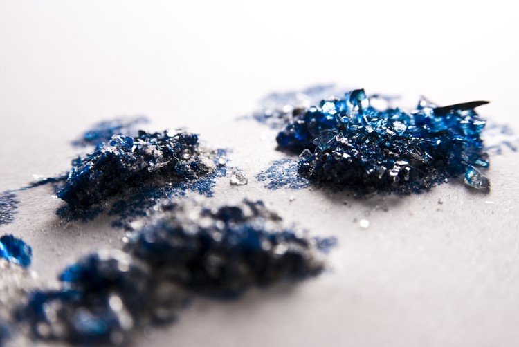 Pulverized glass with blue dye drips appart.