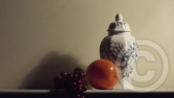 Grapes and orange agaist vase