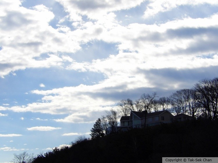 White clouds over the hill of Port Jefferson, NY, at dusk, 03-17-2024