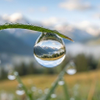 Macro water drop reflects majestic snowy mountains in green meadow